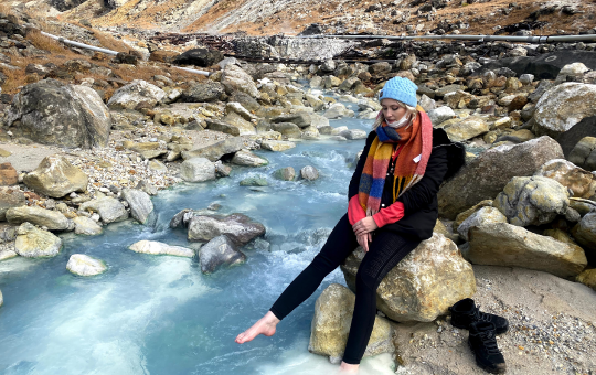 岩場を流れる温泉に足を浸ける女性